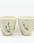 Pair of white porcelain cups splattered with black.