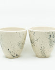 Pair of white porcelain cups splattered with black.