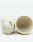 Pair of white porcelain cups splattered with black. Bottom and inside view.