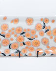 Handmade platter patterned with pink cherry blossom flowers with green and black branches. Front view.