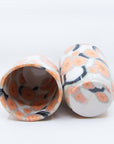 Pair of handmade cups patterned with pink cherry blossom flowers on black branches. Bottom and inside view.