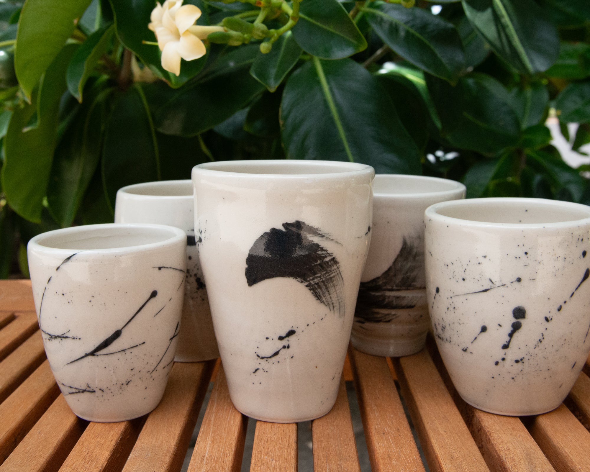 Collection of handmade slip painted cups on white clay. 